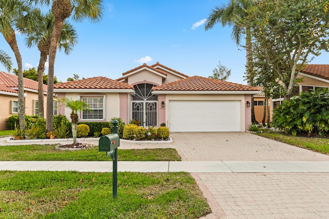 mediterranean / spanish-style house with stucco siding, decorative driveway, a garage, and a tile roof