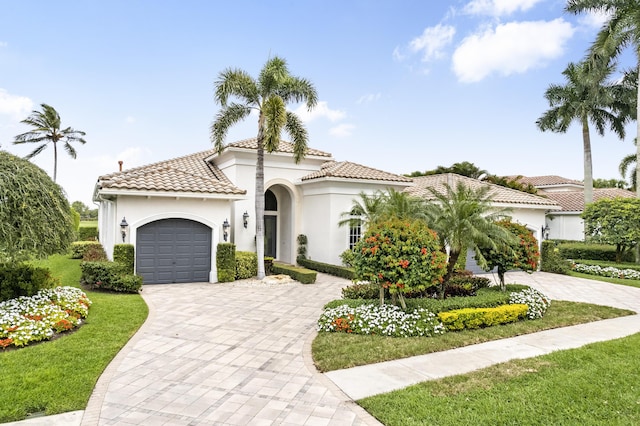 mediterranean / spanish-style house with an attached garage, a tiled roof, decorative driveway, and stucco siding