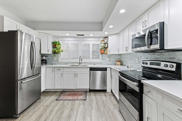 kitchen featuring open shelves, appliances with stainless steel finishes, a sink, and white cabinets