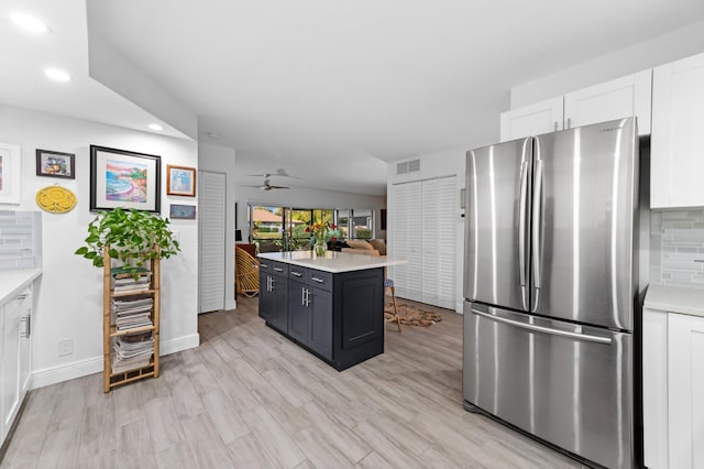 kitchen with light countertops, backsplash, freestanding refrigerator, and white cabinets