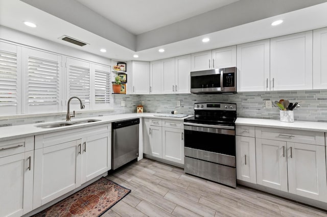 kitchen with light countertops, visible vents, appliances with stainless steel finishes, white cabinetry, and a sink