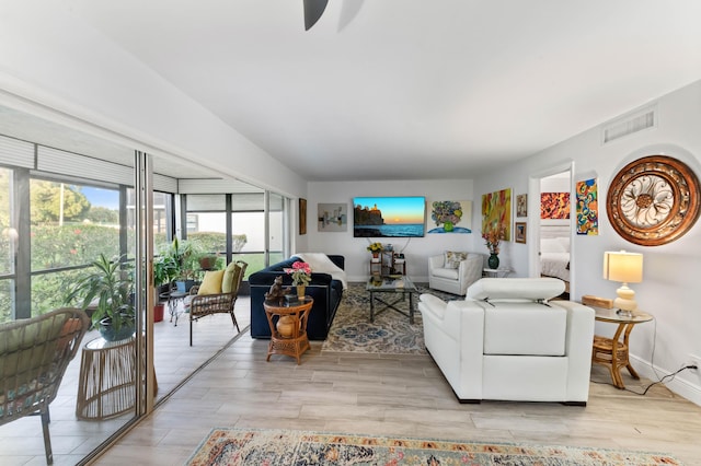 living room with light wood finished floors, baseboards, and visible vents