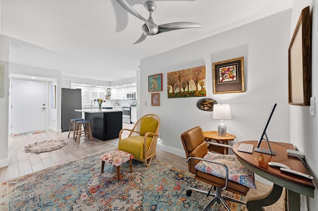 living area featuring light wood-style flooring, baseboards, and a ceiling fan