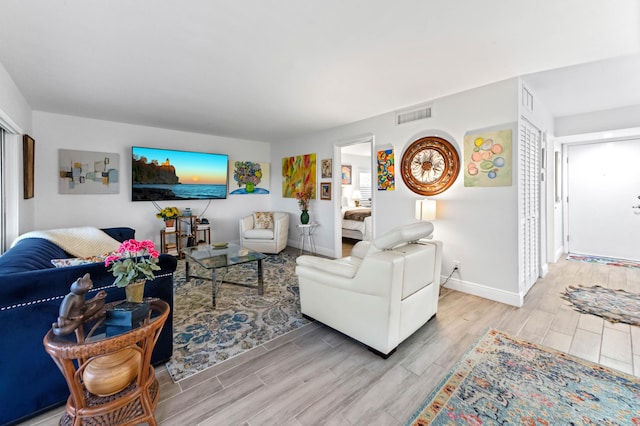 living area featuring baseboards, visible vents, and wood finish floors