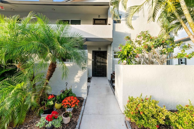 view of exterior entry featuring fence and stucco siding