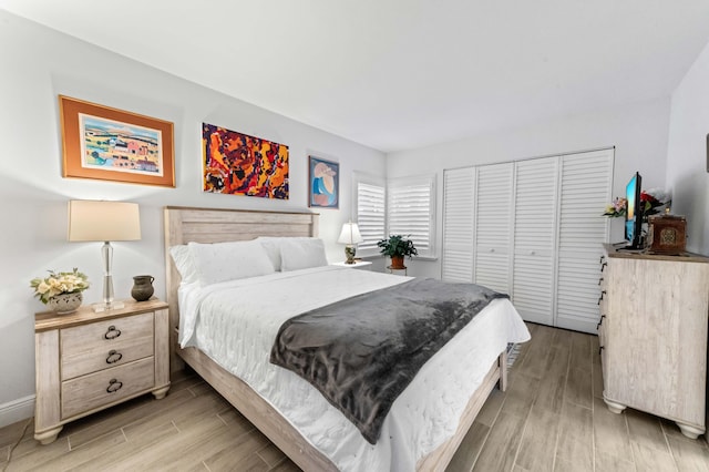 bedroom featuring wood tiled floor, baseboards, and a closet