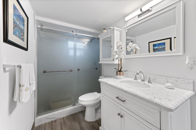 full bath with wood finished floors, a stall shower, vanity, and toilet