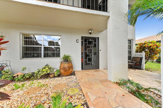 view of exterior entry featuring a patio area and stucco siding