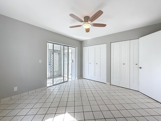 unfurnished bedroom with light tile patterned floors, access to outside, two closets, and a ceiling fan