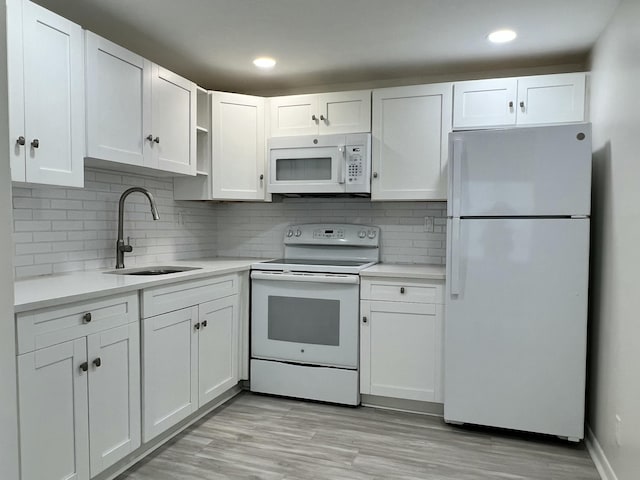 kitchen featuring white appliances, white cabinetry, light countertops, and a sink