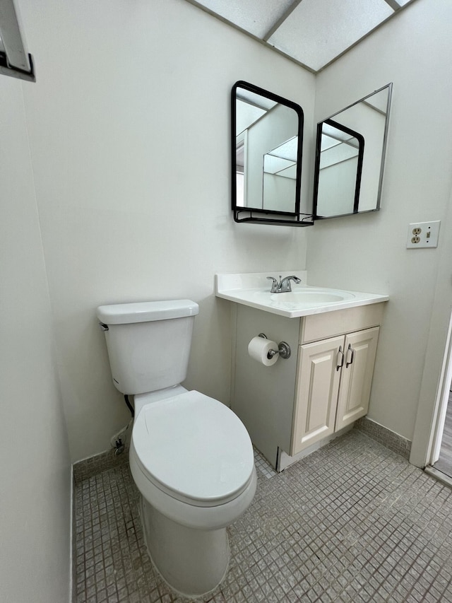 bathroom with toilet, vanity, and baseboards