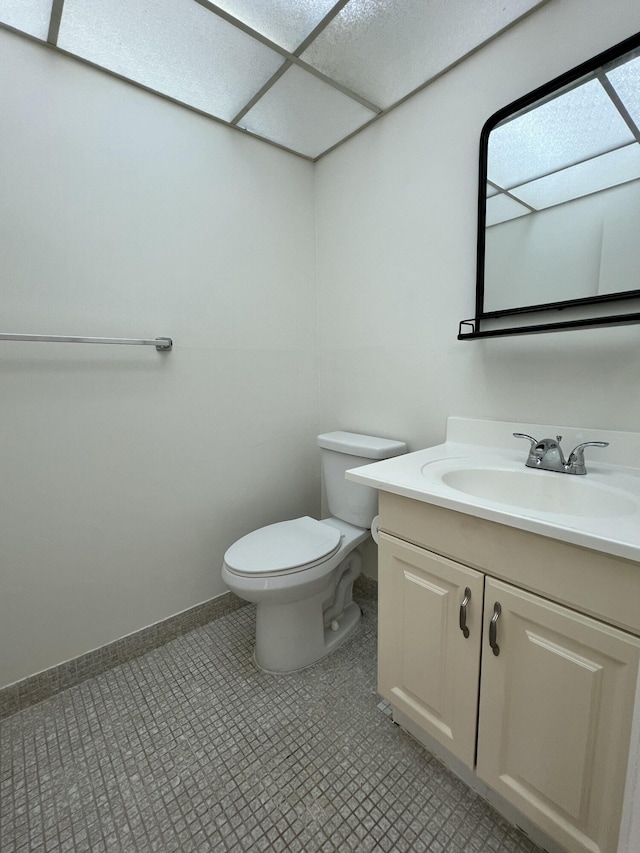 bathroom with toilet, baseboards, and vanity