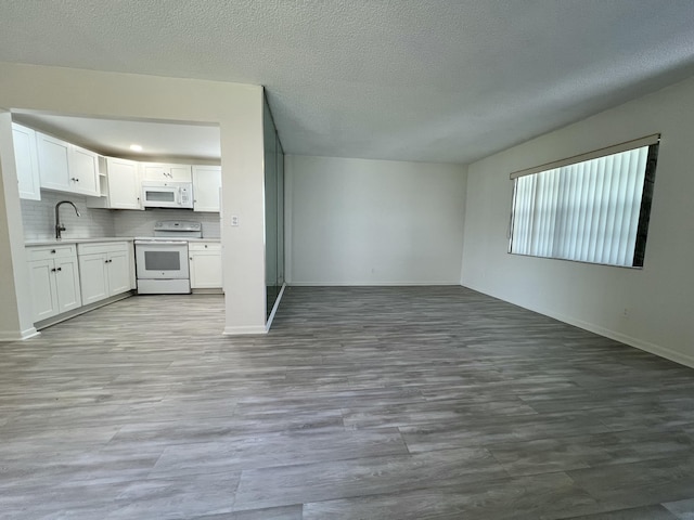 unfurnished living room with baseboards, a textured ceiling, and light wood finished floors