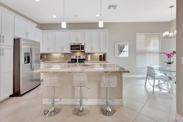 kitchen with pendant lighting, visible vents, appliances with stainless steel finishes, white cabinets, and a sink