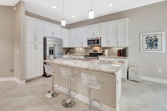 kitchen with stainless steel appliances, white cabinetry, a sink, and an island with sink