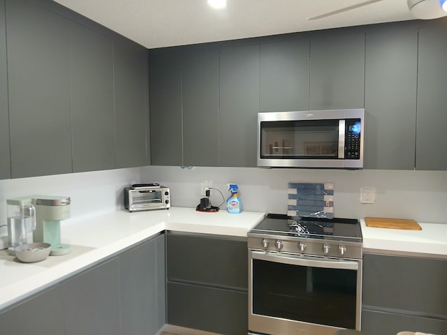 kitchen featuring gray cabinets, modern cabinets, stainless steel appliances, and light countertops