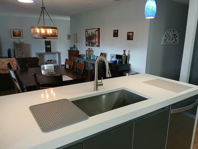 kitchen with black dishwasher, pendant lighting, light countertops, and a sink