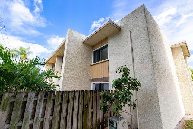 view of property exterior featuring ac unit, fence, and stucco siding