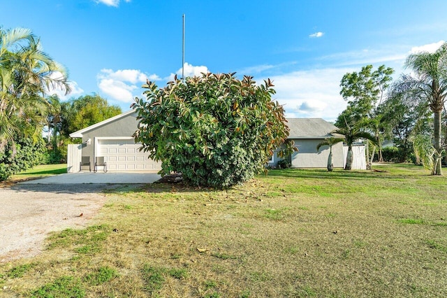 view of front of property with dirt driveway, a front lawn, a garage, and stucco siding