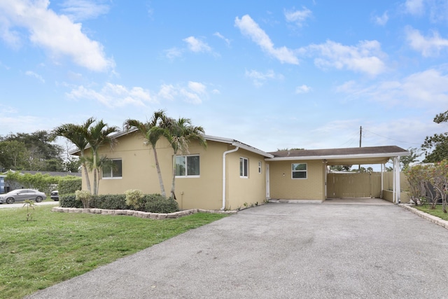 view of front of home featuring driveway, a carport, a front yard, and stucco siding