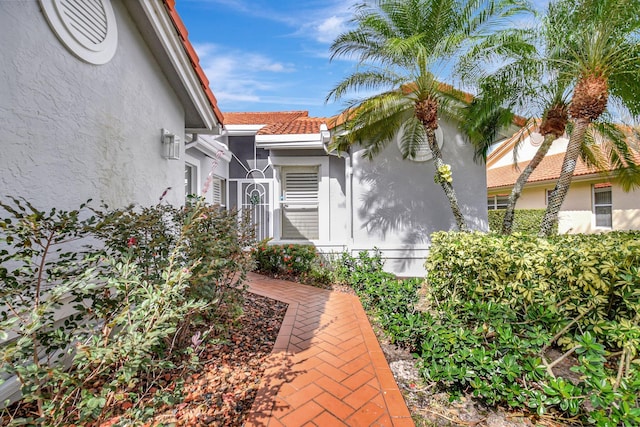 entrance to property featuring a tiled roof and stucco siding