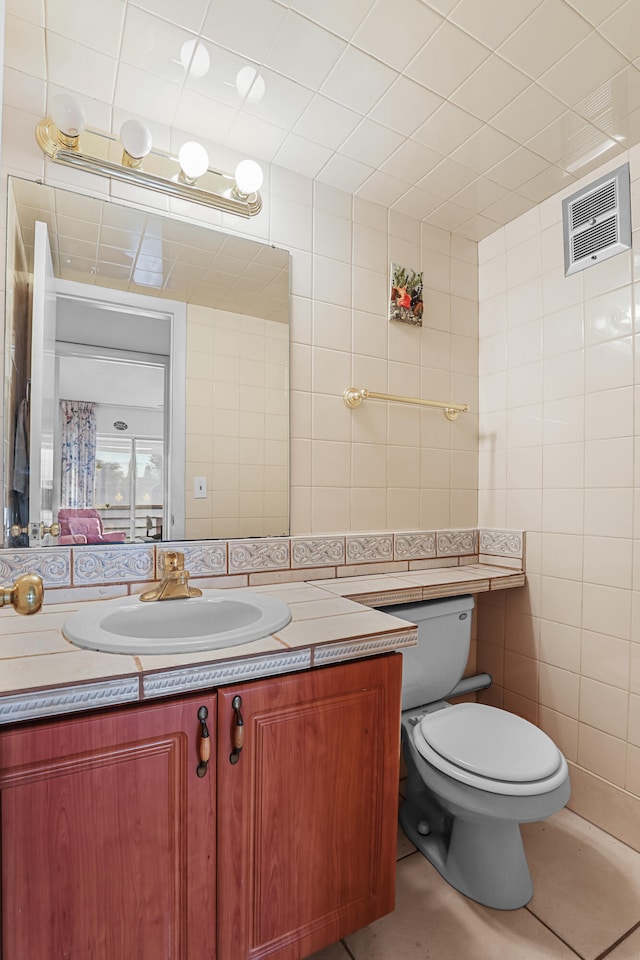 bathroom featuring tile walls, visible vents, toilet, vanity, and tile patterned floors