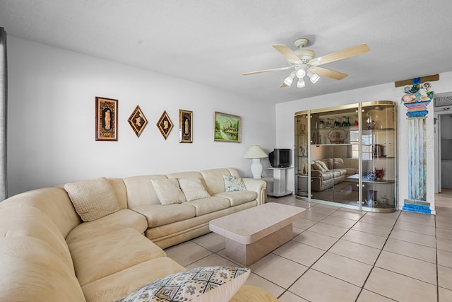 living room with light tile patterned floors, ceiling fan, and a textured ceiling