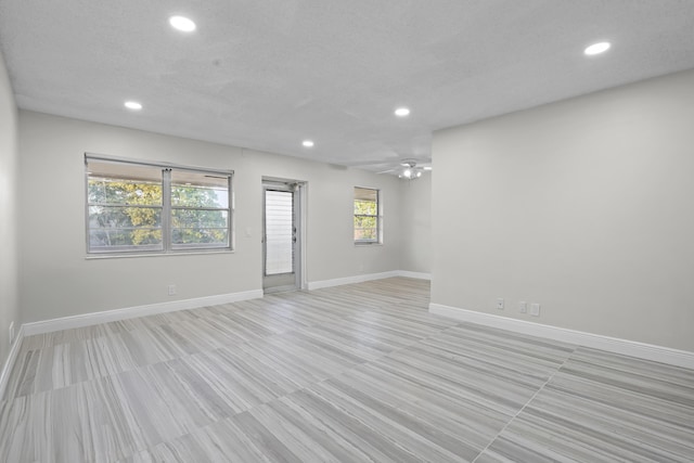 unfurnished room featuring baseboards, a textured ceiling, and recessed lighting