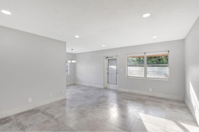 unfurnished room with recessed lighting, a notable chandelier, a textured ceiling, and baseboards