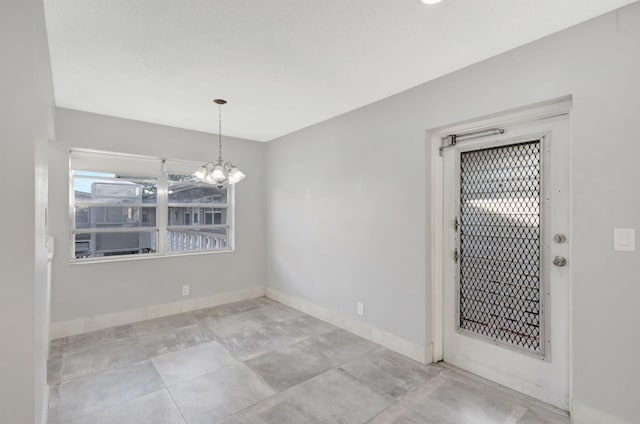 unfurnished room with an inviting chandelier and baseboards