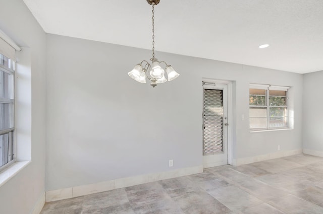 unfurnished room with a chandelier and baseboards