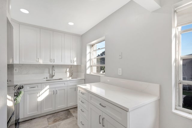 kitchen with electric range oven, light countertops, a sink, and white cabinetry