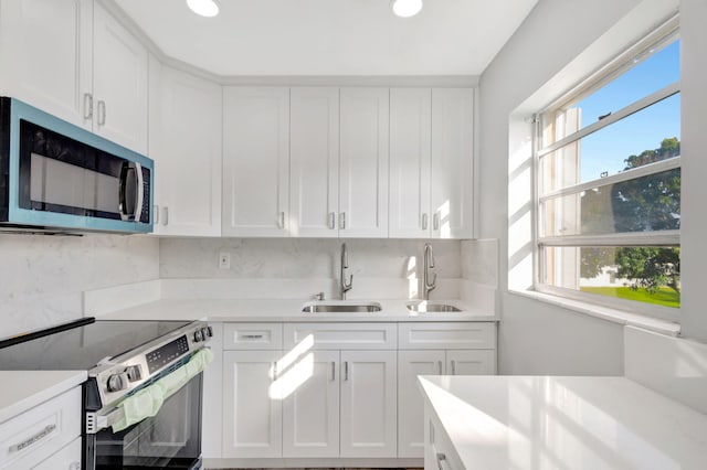 kitchen with white cabinets, appliances with stainless steel finishes, light countertops, and a sink