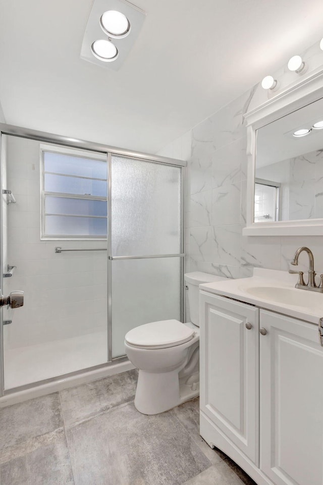 bathroom featuring toilet, tile walls, a shower stall, and vanity