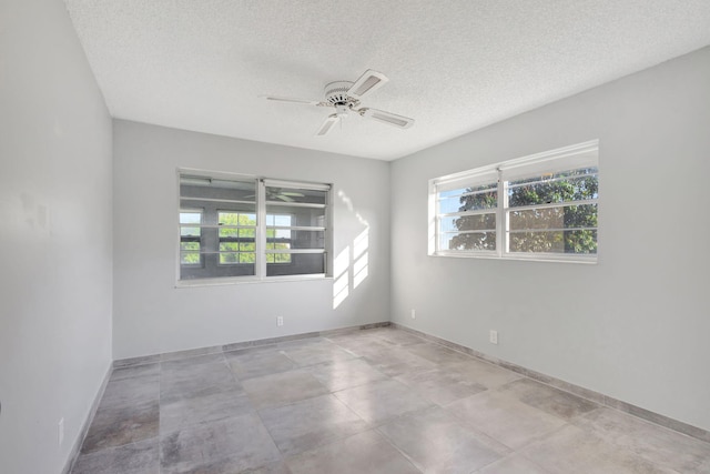 unfurnished room with plenty of natural light, baseboards, ceiling fan, and a textured ceiling