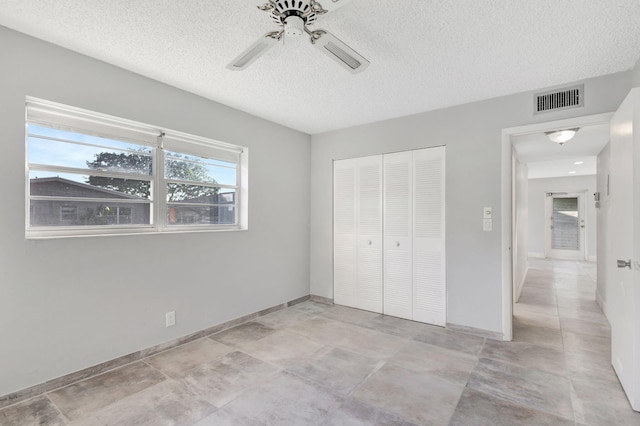 unfurnished bedroom with a closet, visible vents, ceiling fan, a textured ceiling, and baseboards