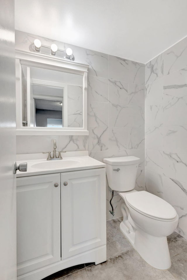 half bathroom featuring marble finish floor, vanity, and toilet