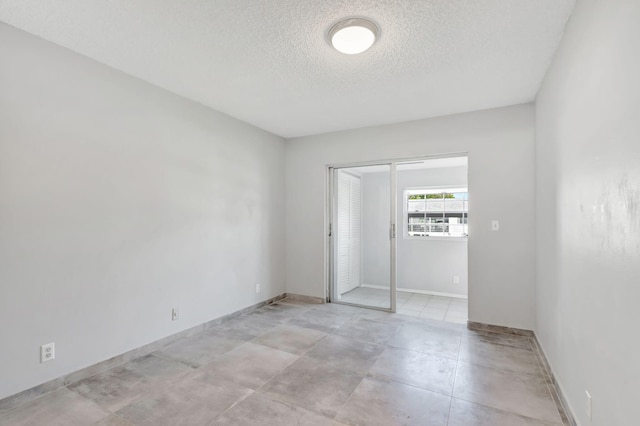 empty room featuring a textured ceiling and baseboards