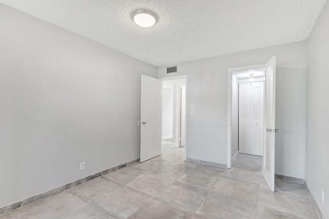 unfurnished bedroom featuring visible vents, baseboards, and a textured ceiling