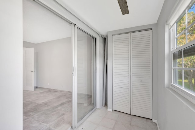 corridor featuring baseboards and light tile patterned flooring