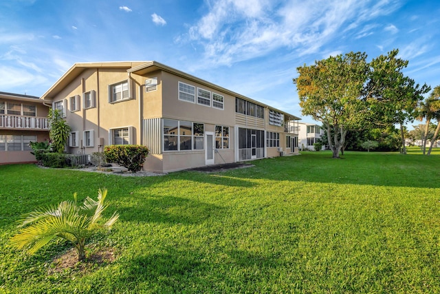 rear view of property featuring a lawn and stucco siding