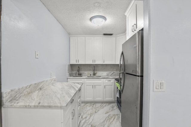 kitchen featuring marble finish floor, freestanding refrigerator, white cabinets, a sink, and range