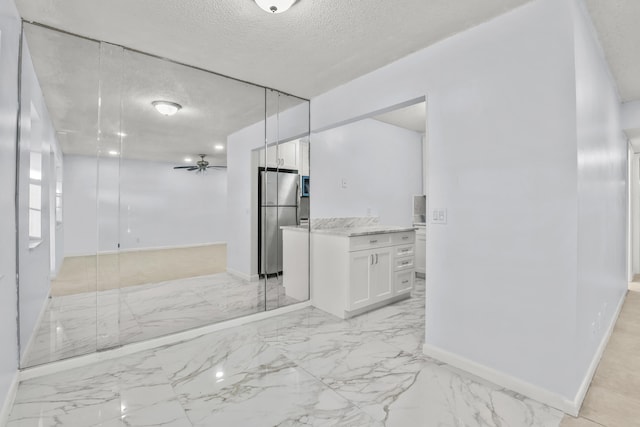 bathroom with marble finish floor, ceiling fan, baseboards, and a textured ceiling