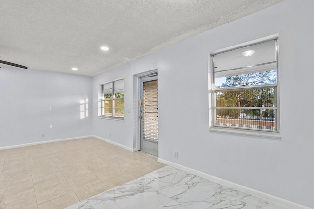 empty room with marble finish floor, recessed lighting, a ceiling fan, a textured ceiling, and baseboards