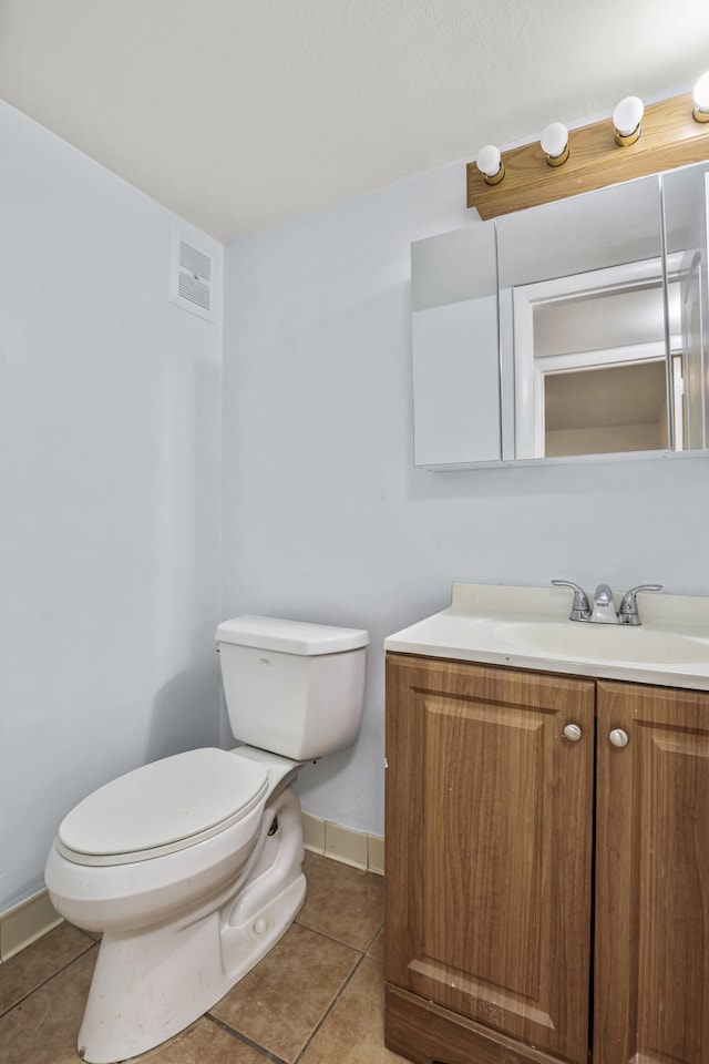 half bath with toilet, vanity, baseboards, visible vents, and tile patterned floors