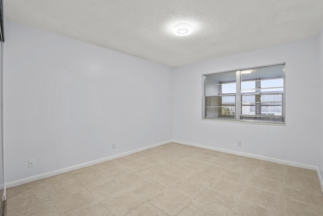 empty room featuring baseboards and a textured ceiling