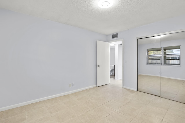 unfurnished bedroom featuring baseboards, a textured ceiling, visible vents, and a closet