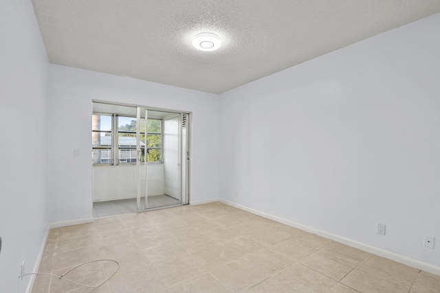 unfurnished room with baseboards and a textured ceiling