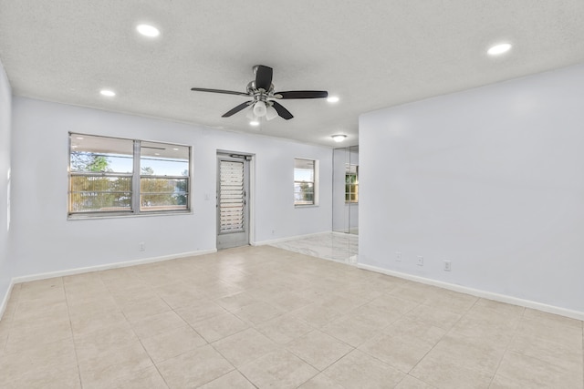 empty room featuring ceiling fan, a textured ceiling, and baseboards