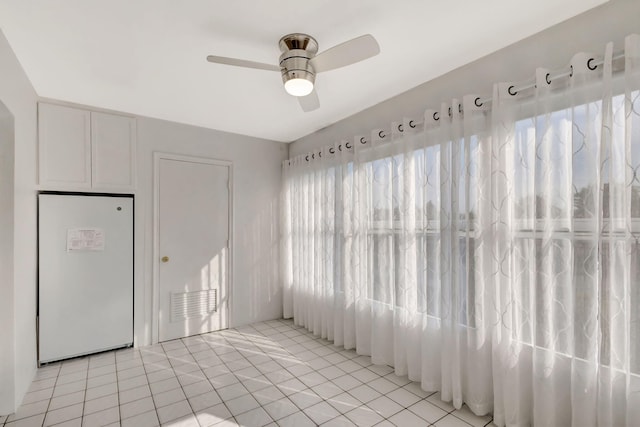 empty room with light tile patterned floors and a ceiling fan